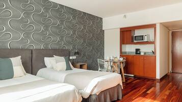 Habitación de hotel con dos camas, kitchenette y zona de comedor.