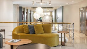 Un vestíbulo moderno con un sofá amarillo, una mesa redonda y una escalera.