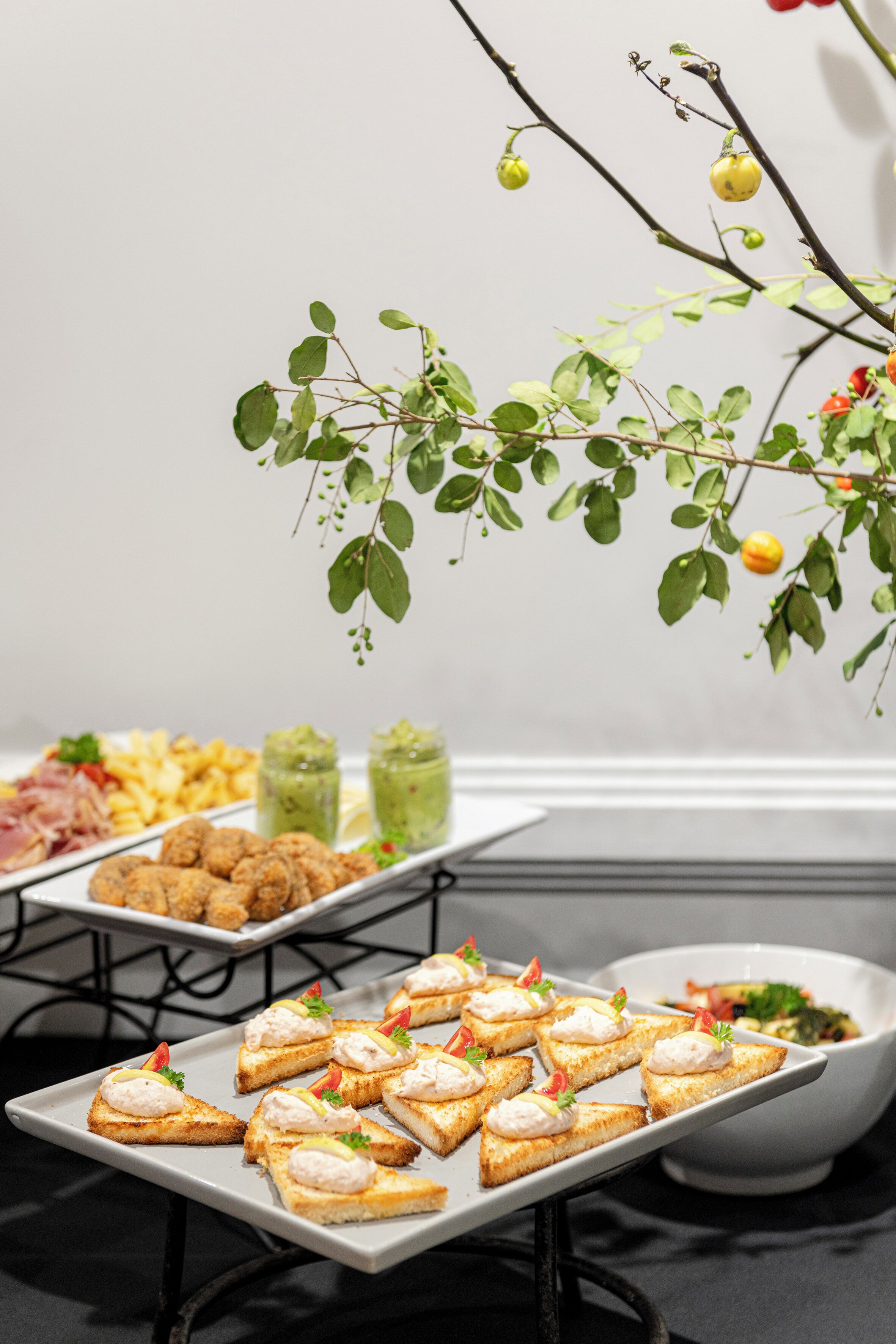A buffet table with various food items and a decorative plant branch.