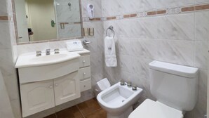 Une salle de bain moderne avec un lavabo blanc, un miroir et deux toilettes.