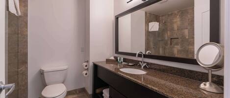A modern bathroom with a toilet, sink, and large mirror.