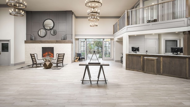 A spacious living area with a fireplace, a dining table, and a balcony with a railing. - Prestige Rocky Mountain Resort Cranbrook, WorldHotels Crafted (Cranbrook)