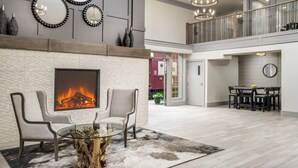A spacious living area with a fireplace, two armchairs, a glass coffee table, and a modern chandelier. - Prestige Rocky Mountain Resort Cranbrook, WorldHotels Crafted (Cranbrook)