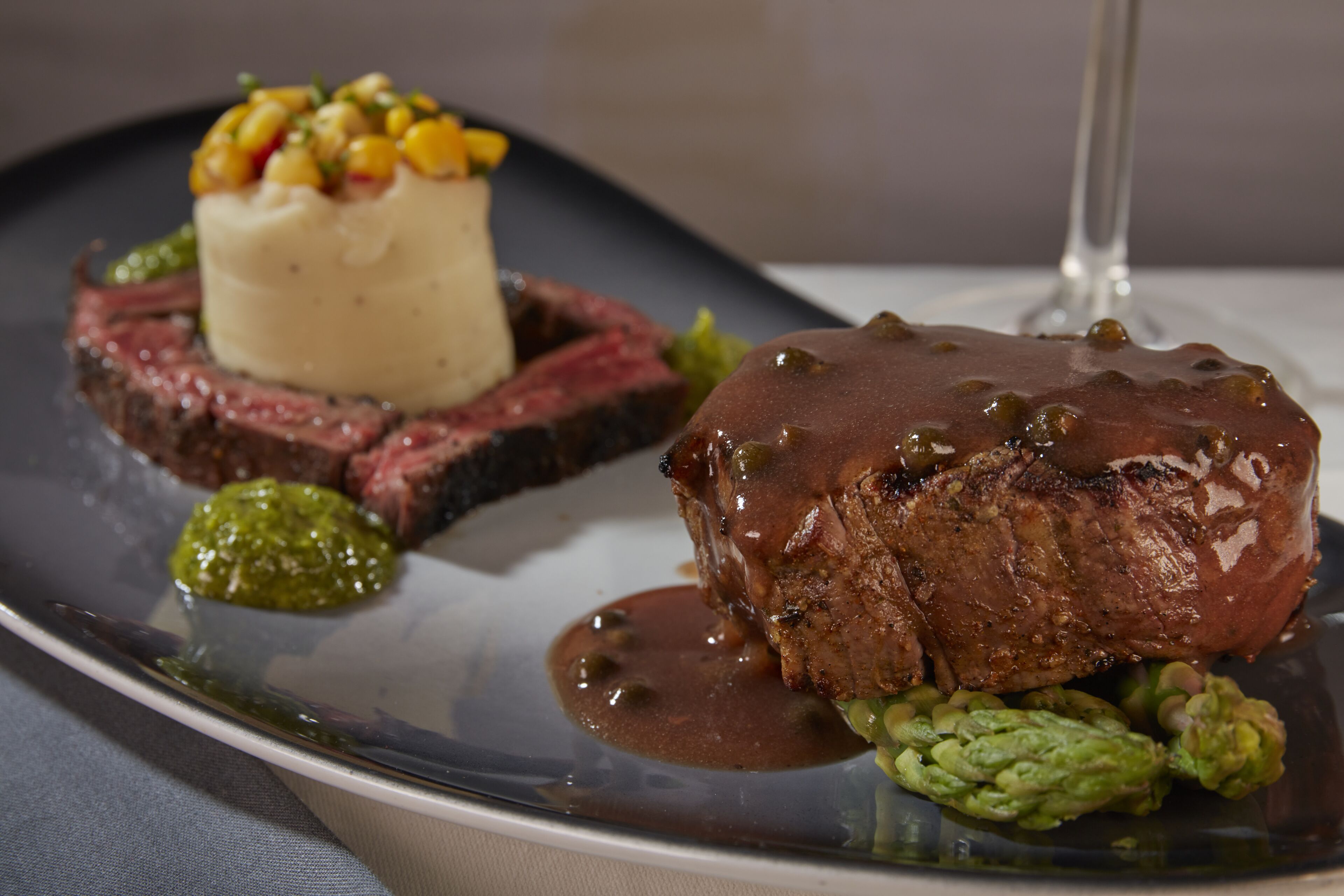 A plate of food with a steak and a mound of corn.