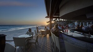 A beachside bar with outdoor seating overlooking the ocean.