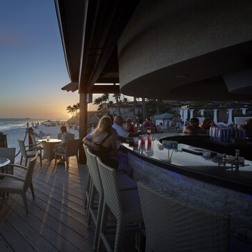 A beachside bar with outdoor seating overlooking the ocean.