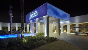 A modern hotel with a pool, palm trees, and a sign that reads "Diva Aqua Resort".
