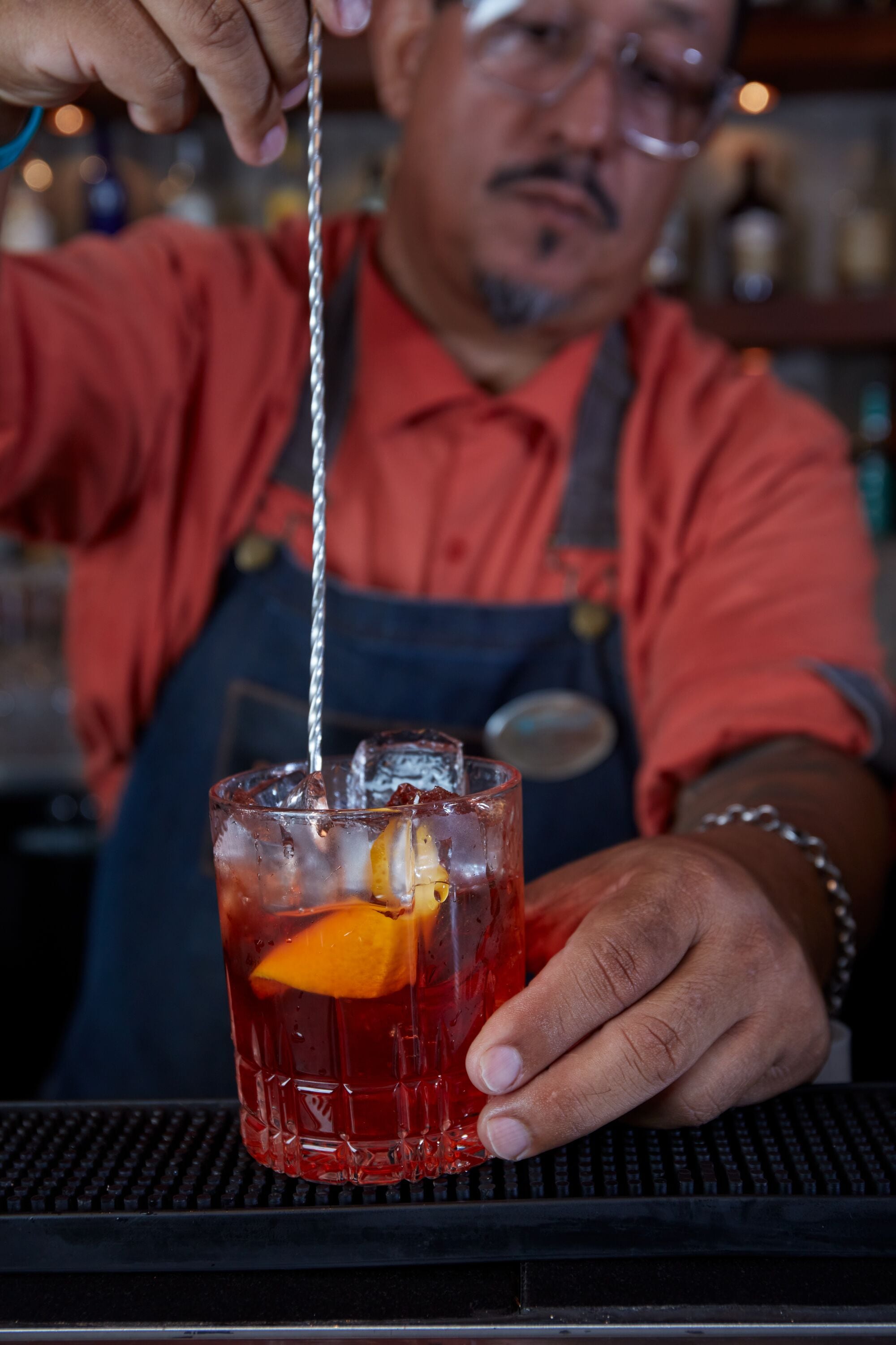 A person pouring a drink into a glass with an orange slice.