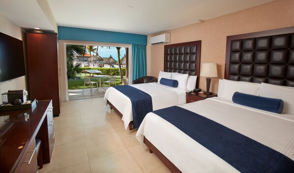 A hotel room with two beds, a TV, a desk, and a view of a pool and resort.