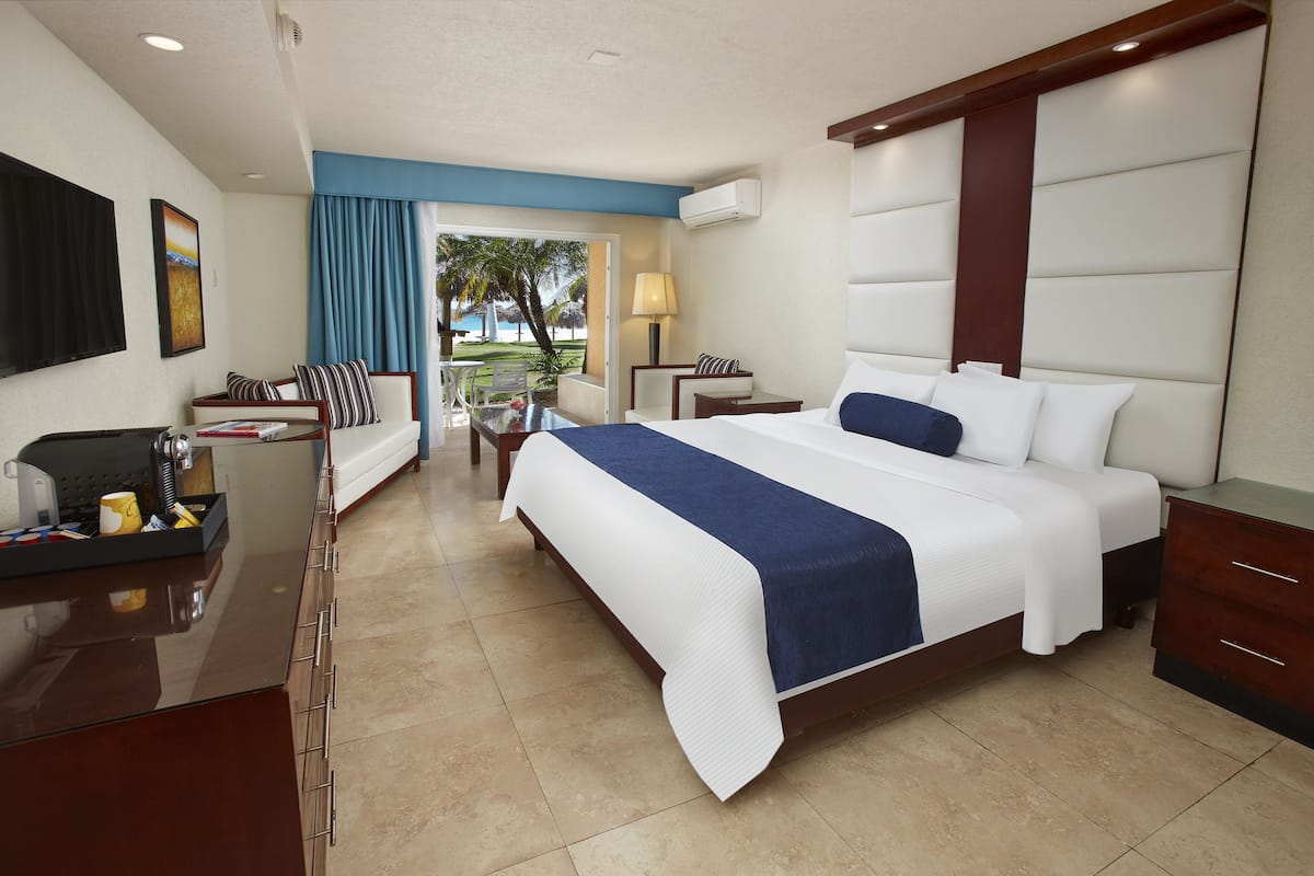 A hotel room with a large bed, a desk, a chair, a TV, and a view of the outdoors.
