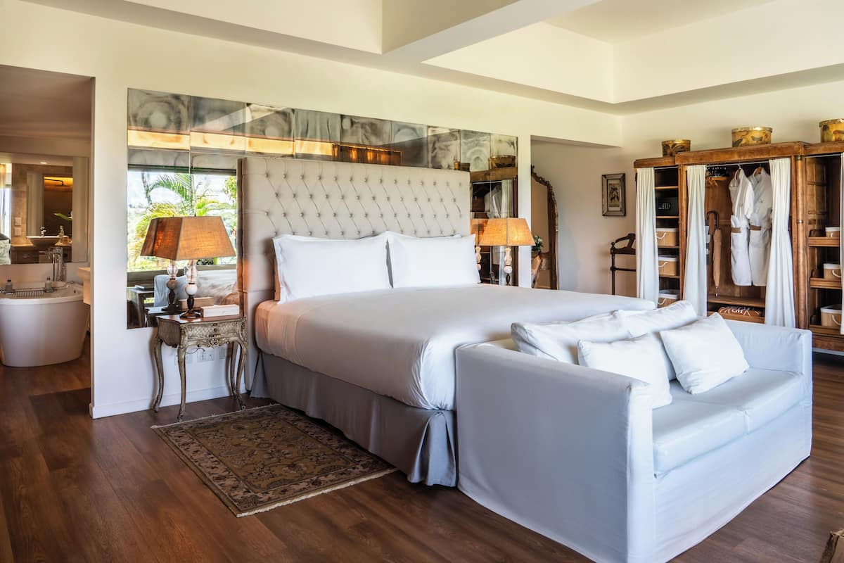 A spacious bedroom with a large bed, a sitting area, and a wardrobe.