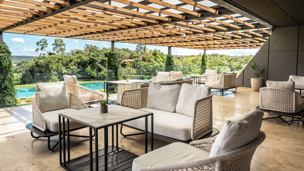 An outdoor patio area with wicker furniture, a pool, and a view of the surrounding greenery. - Gran Melia Iguazú (Puerto Iguazú)