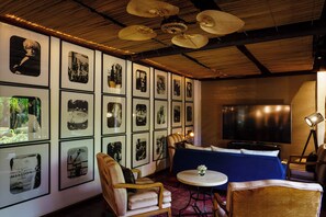 A room with a large TV, framed pictures on the wall, a sofa, and a small round table.