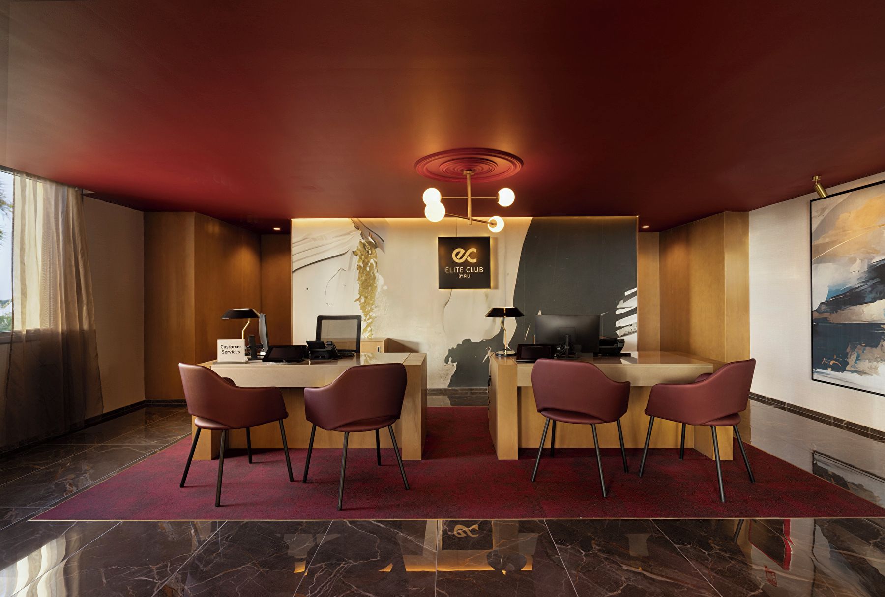 A hotel reception area with a marble floor, red carpet, and modern furniture.