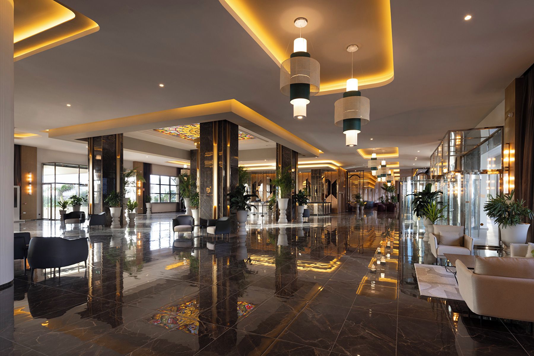 A spacious lobby with a polished marble floor, seating areas, and modern lighting fixtures.