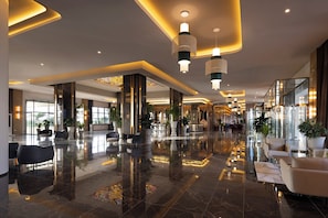 A spacious lobby with a polished marble floor, seating areas, and modern lighting fixtures.