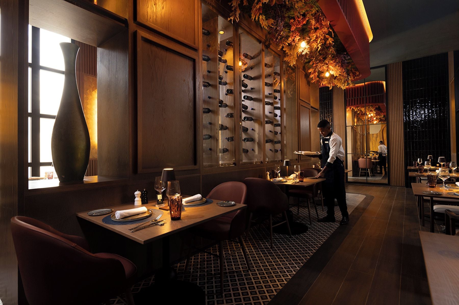 L’intérieur d’un restaurant, avec une cave à vin, des tables et des chaises.
