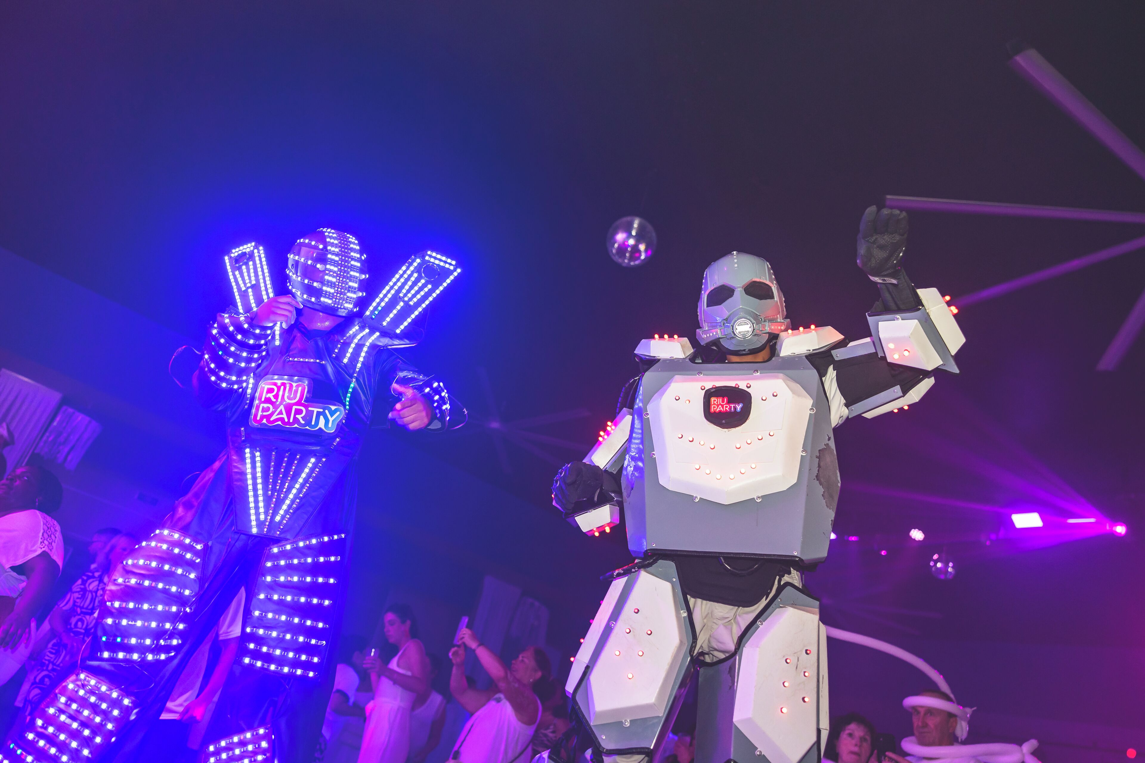 Un robot con luces LED y un cartel que dice 'BJI PARTY', rodeado de gente.