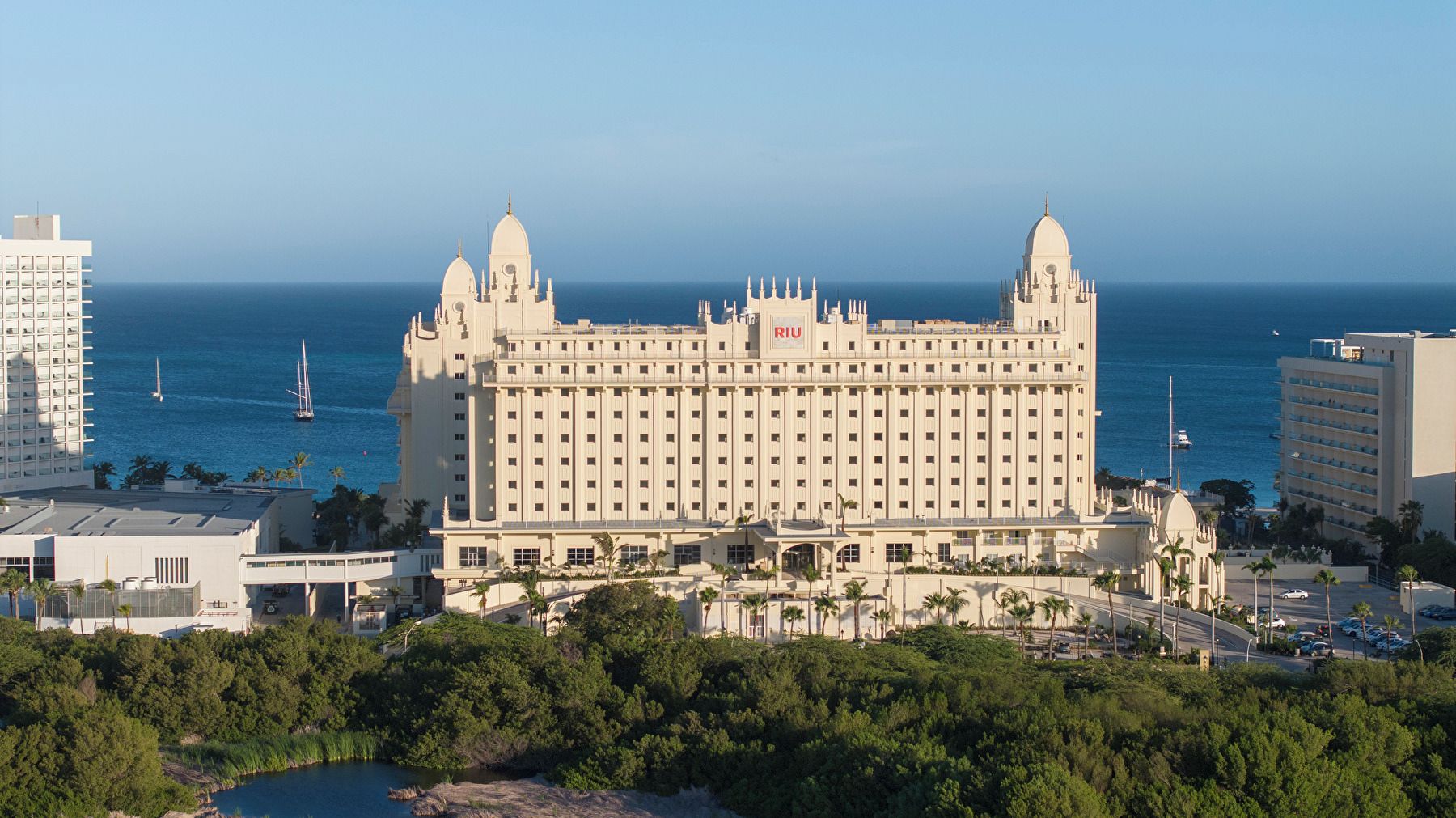 A large hotel with multiple towers, a marina with boats, and a view of the ocean.