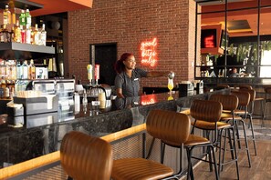 A bar area with a bartender, a neon sign, and a variety of bottles. - Hotel Riu Palace Aruba - All Inclusive (Noord)