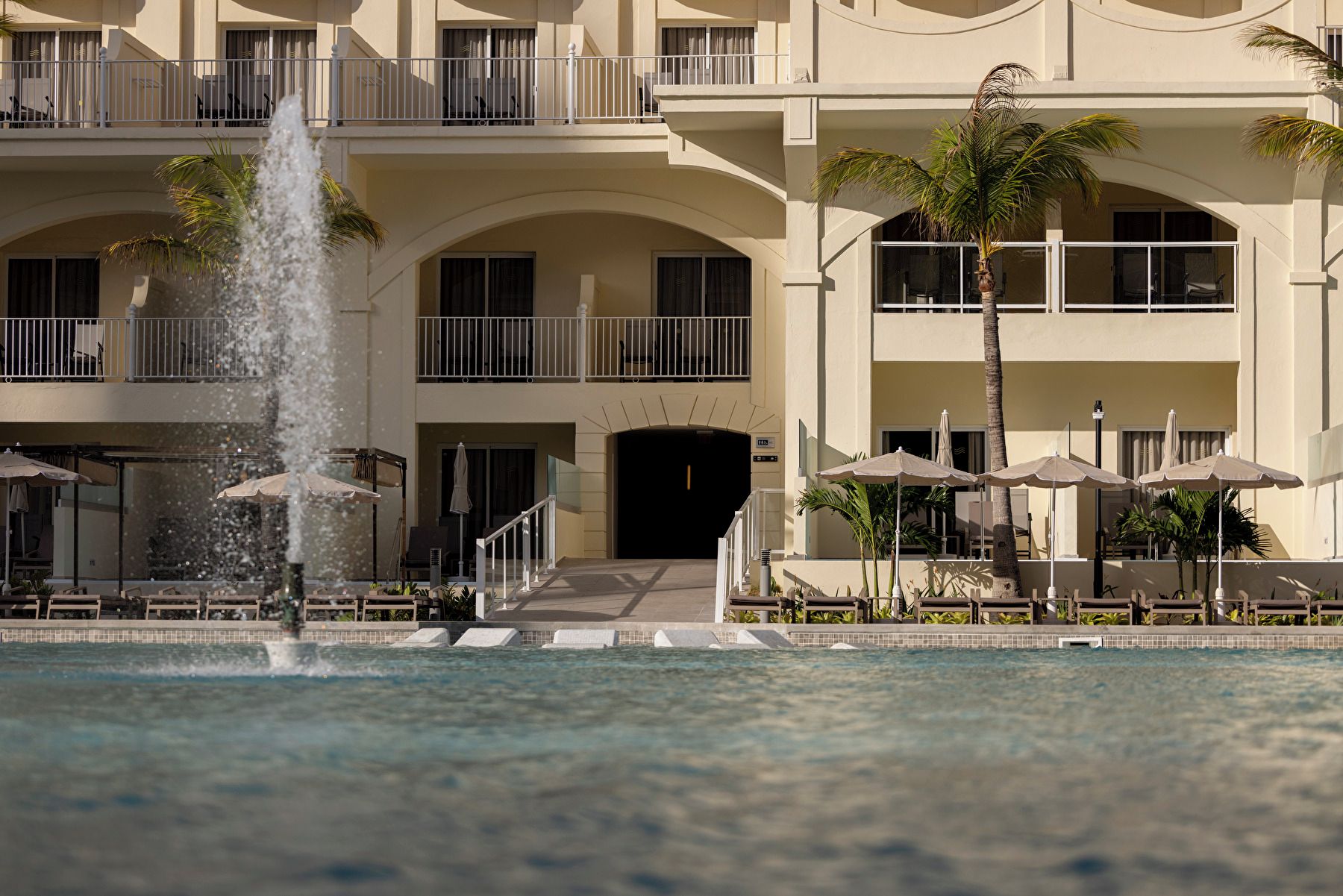 A hotel with a pool, a fountain, and multiple balconies.