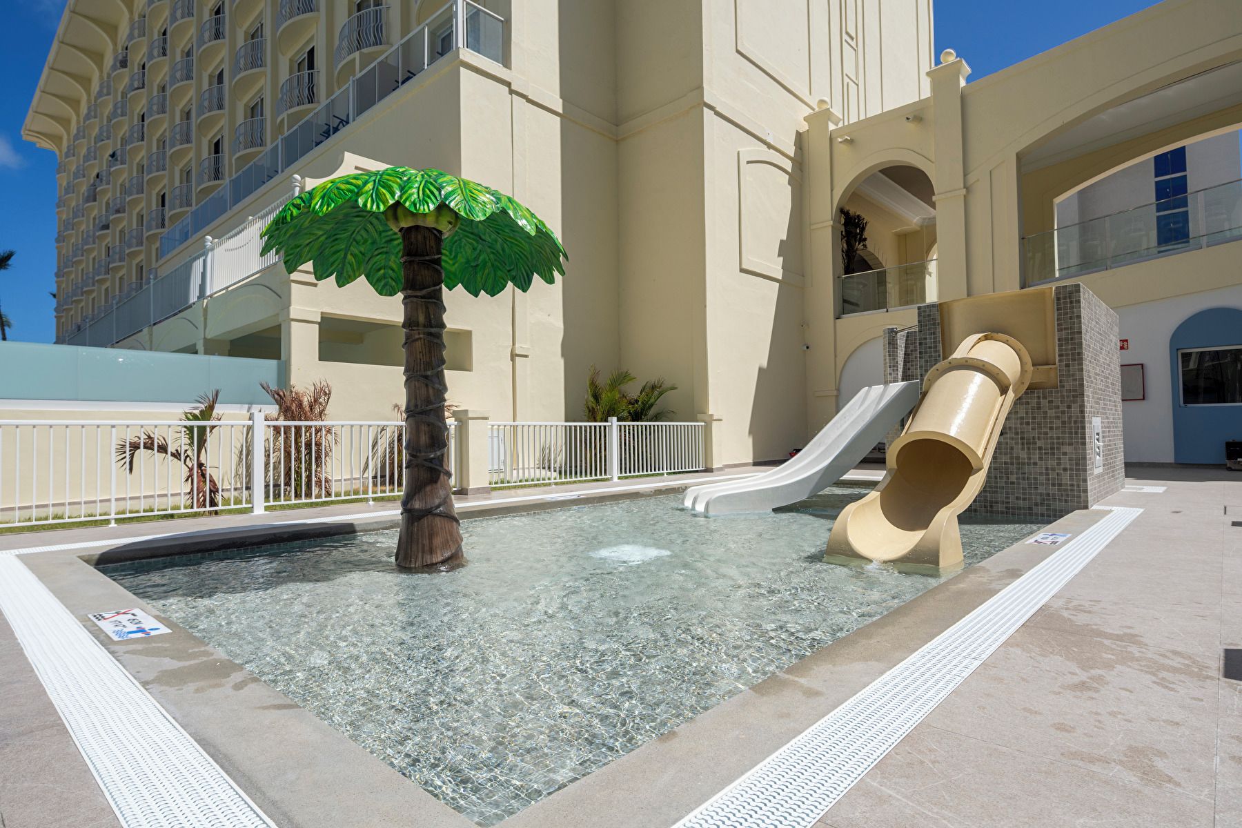 Piscina com escorrega e uma árvore ornamental.