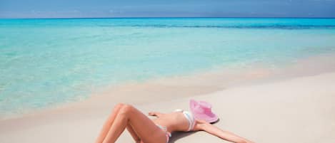 På stranden, hvidt sand, liggestole, parasoller