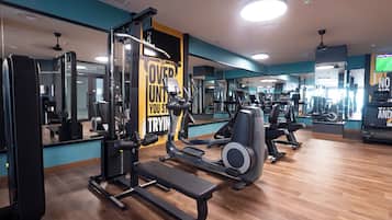 Ein Fitnessstudio mit Trainingsgeräten, Spiegeln und Holzboden.
