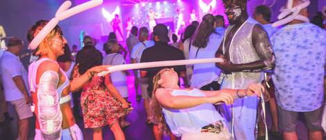 A crowded indoor event with people holding white balloons.