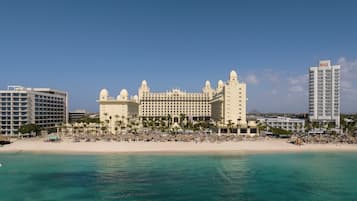 A large resort hotel with multiple buildings, a beach, and a clear blue sky.