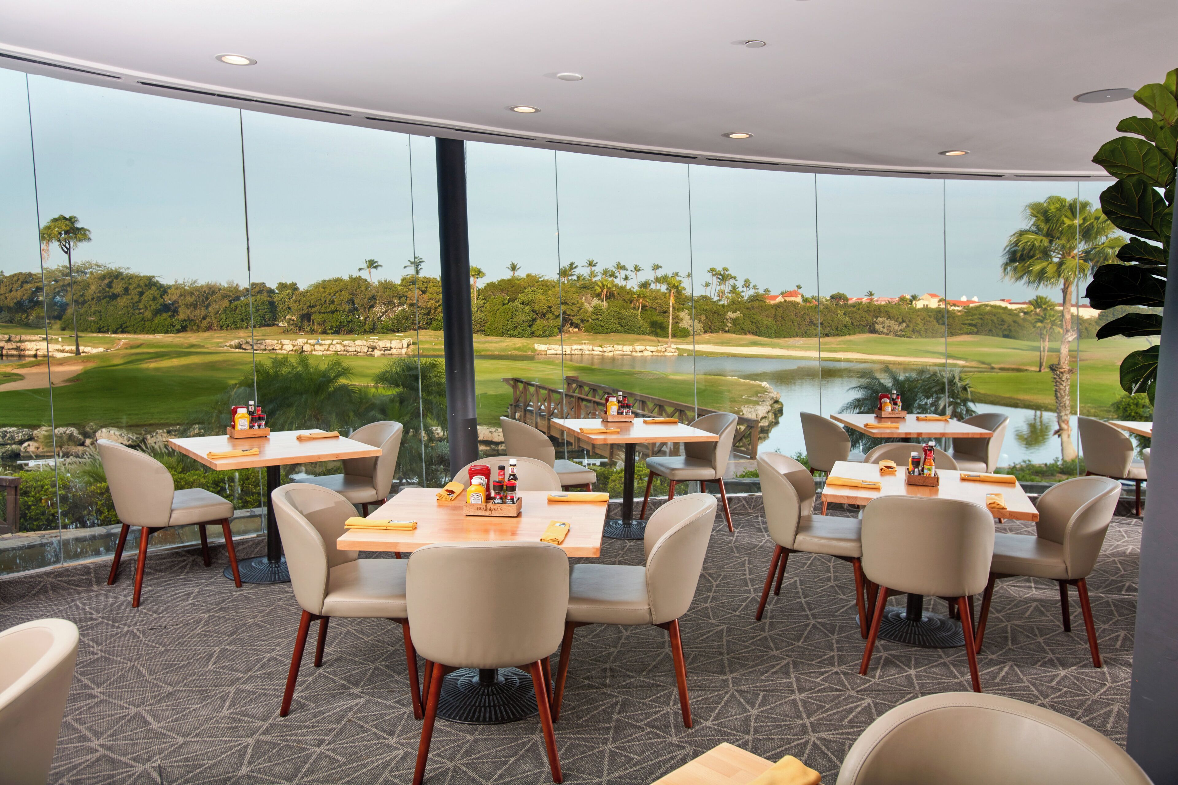 A restaurant with outdoor seating overlooking a golf course and water.