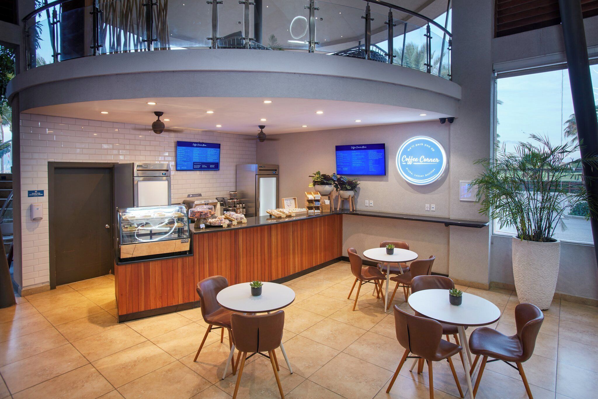 A modern cafe with a curved counter, seating area, and digital menu displays.
