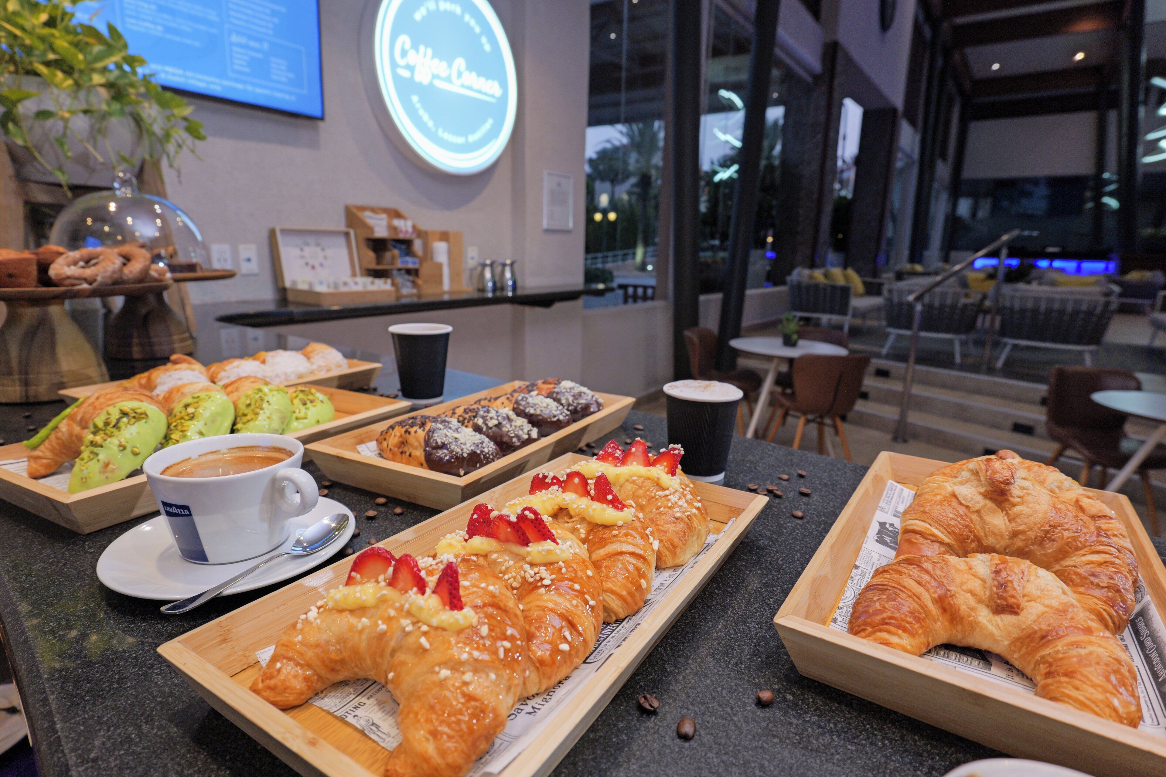 A café with a variety of pastries and coffee, a coffee machine, and a menu board.