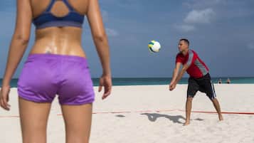 Un partido de voleibol de playa con jugadores vestidos de morado y rojo.