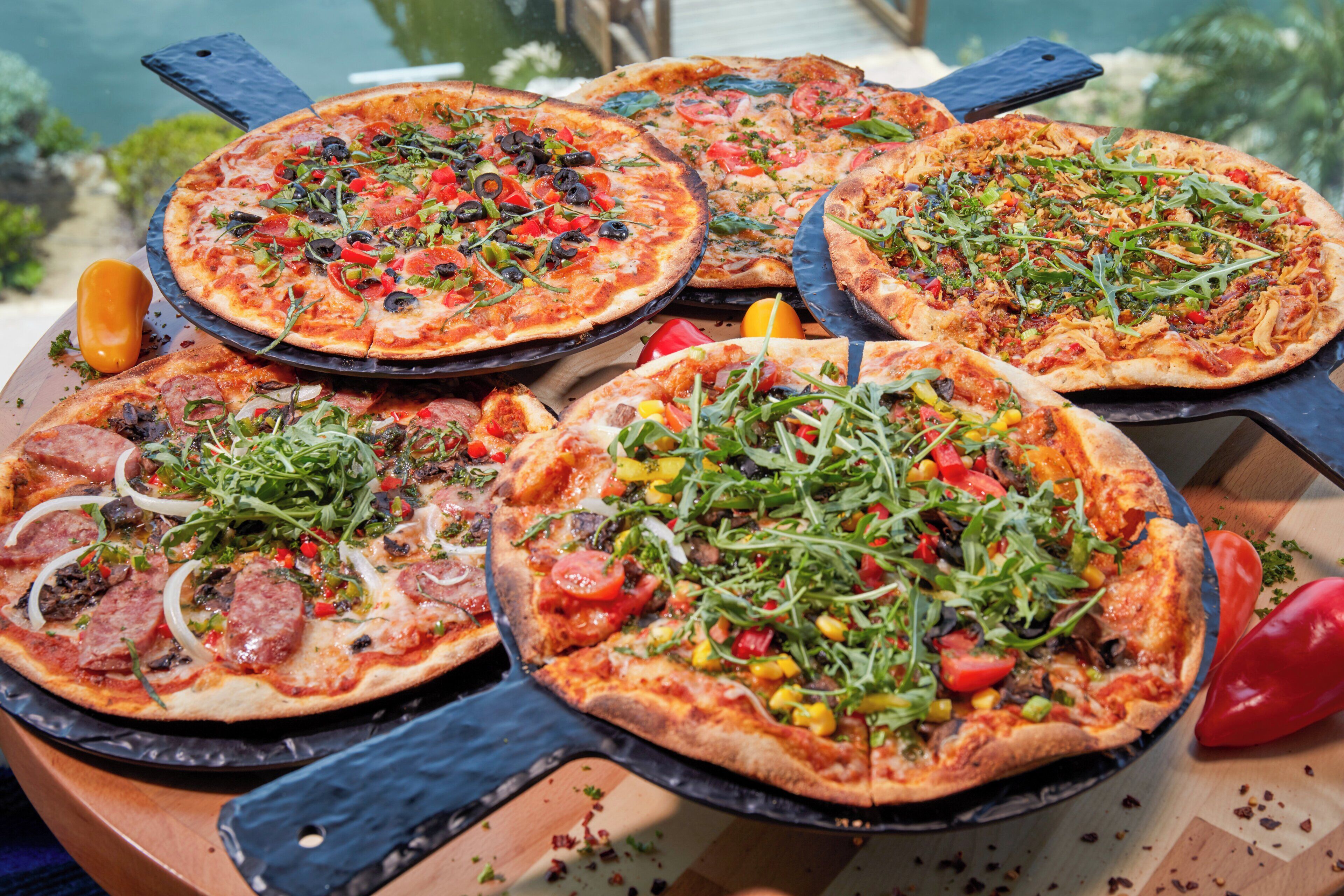 Variedad de pizzas con distintos ingredientes sobre una mesa de madera.