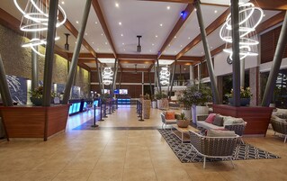 Un vestíbulo amplio con una recepción, zona de estar e iluminación moderna.