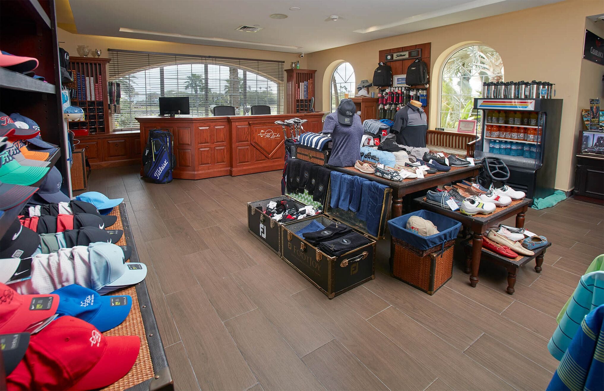 A spacious room with a large wooden desk, a computer, and various items on shelves and tables.