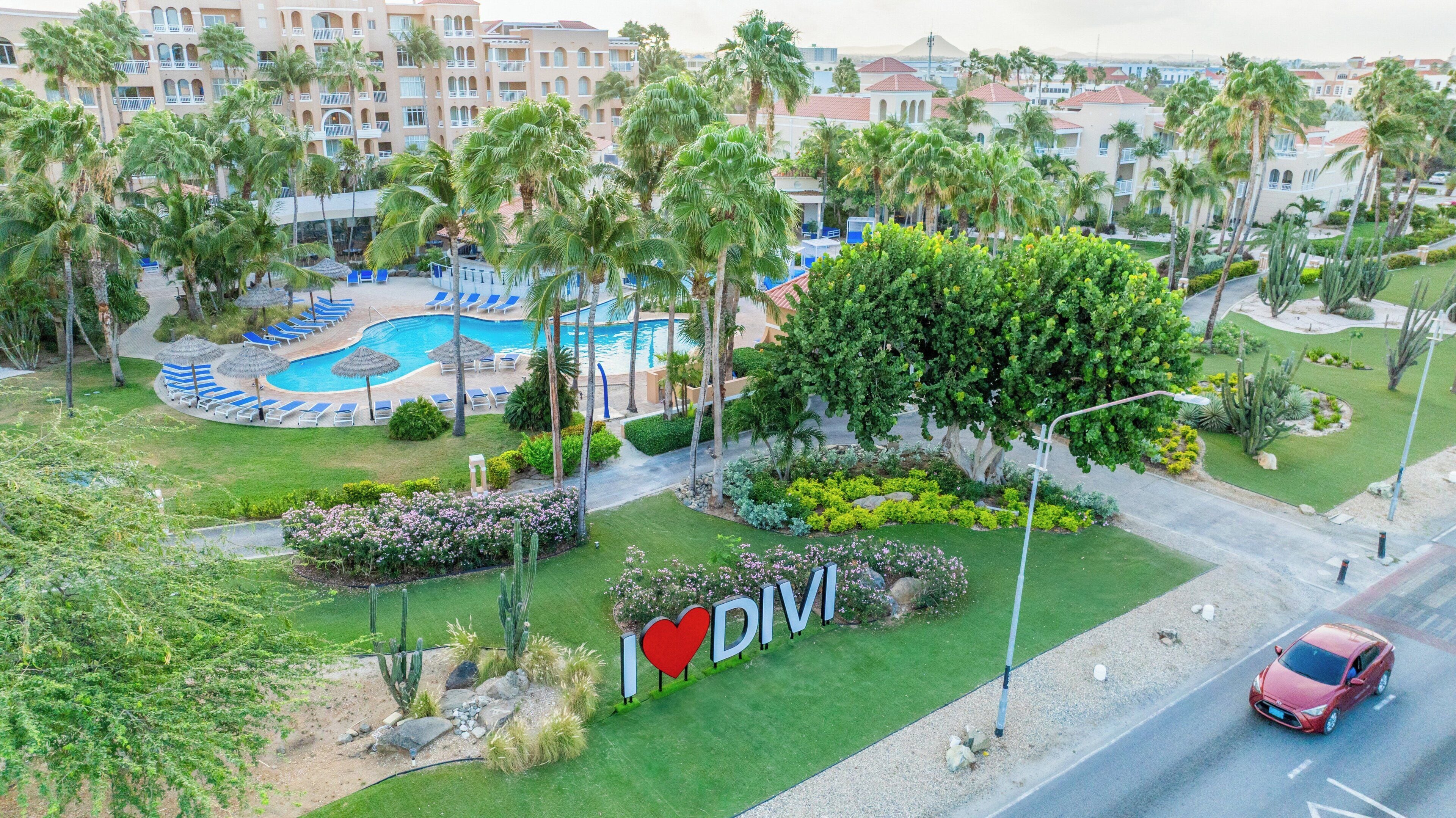 A resort with a pool, palm trees, and a sign that says 'I ♥ DIVI'.