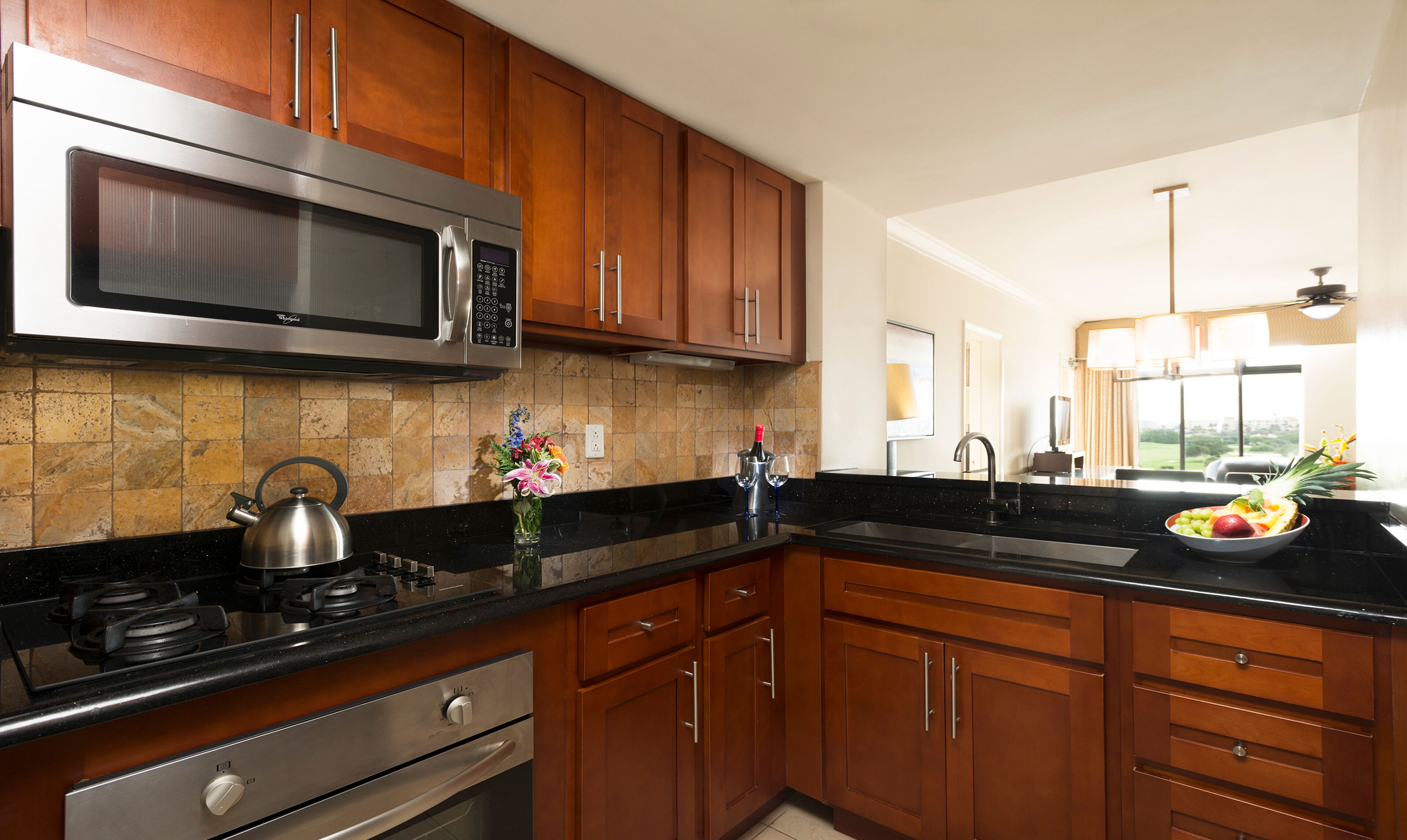 A modern kitchen with wooden cabinets, a stainless steel microwave, and a gas stove.