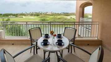 A round table with four blue bowls and a vase with flowers on a balcony overlooking a golf course.
