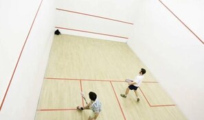 Un court de squash doté d’un plancher en bois et de lignes de démarcation rouges.