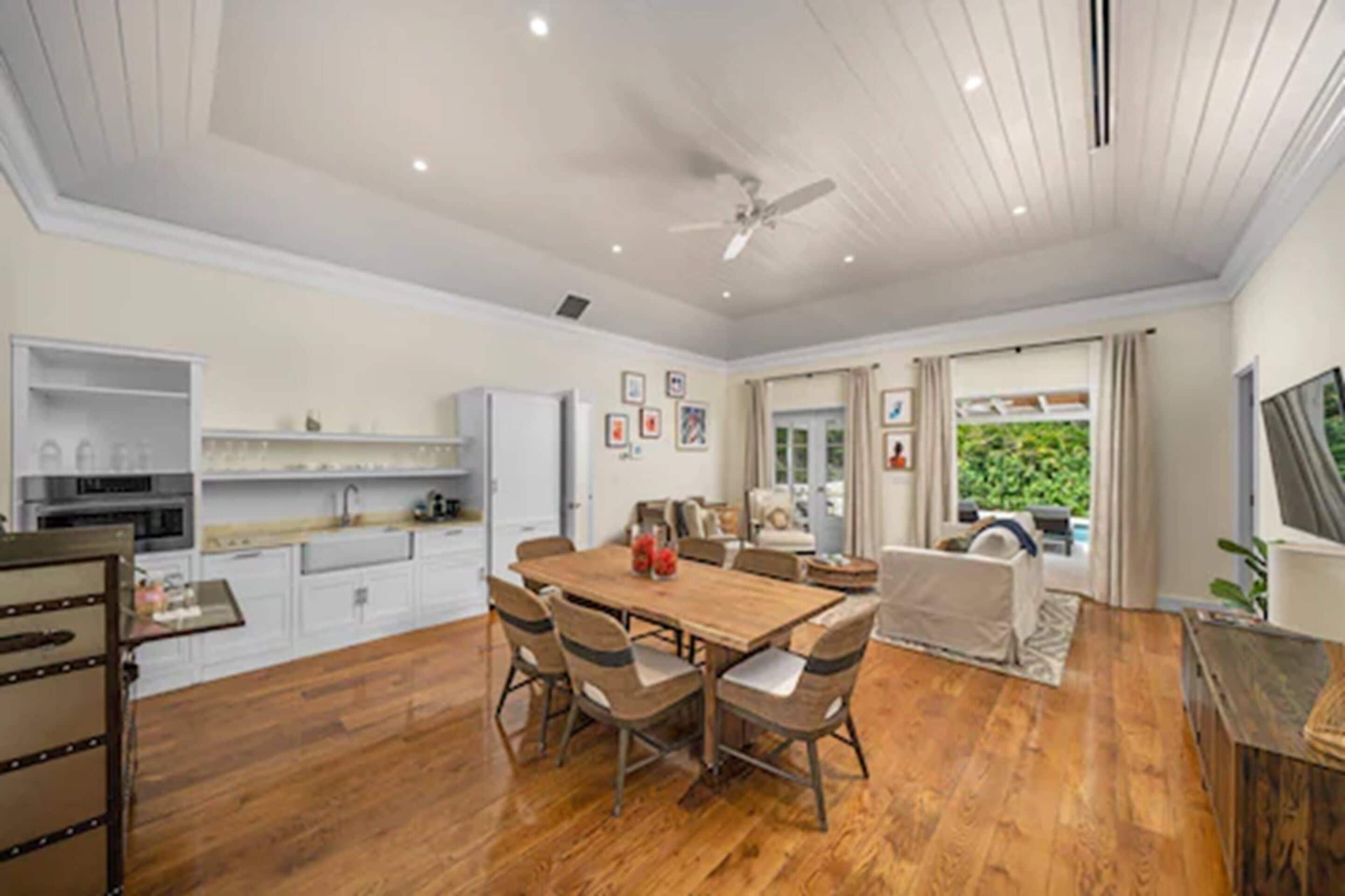 A spacious kitchen with a dining area, wooden flooring, and a ceiling fan.