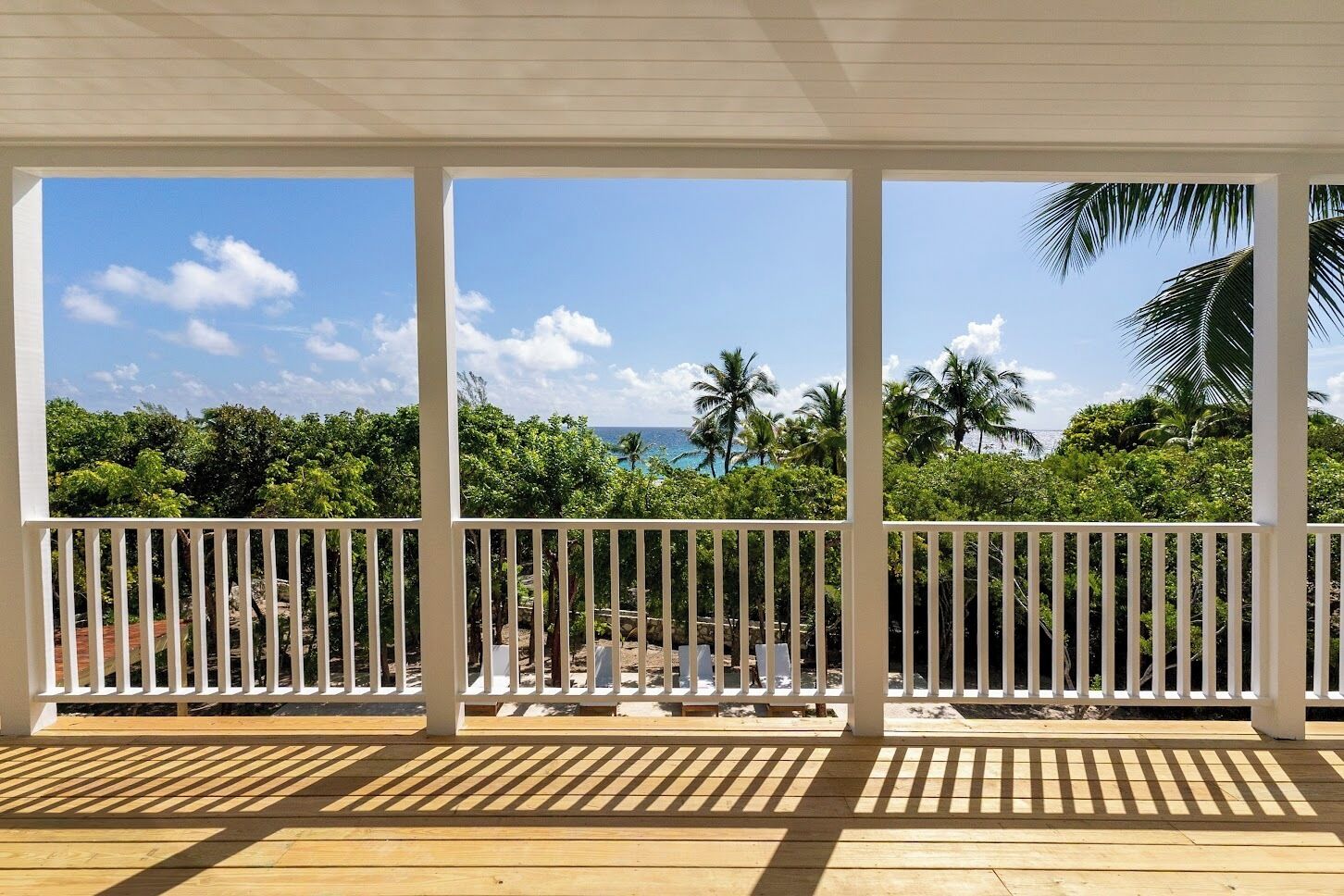 A covered outdoor area with a wooden deck and white railings.