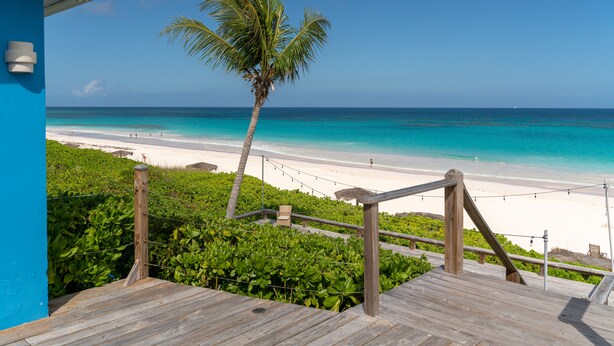 A wooden deck with a view of a beach and ocean. - Pink Sands Resort (Dunmore Town)