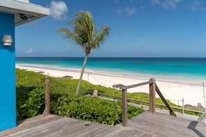 A wooden deck with a view of a beach and ocean. - Pink Sands Resort (Dunmore Town)
