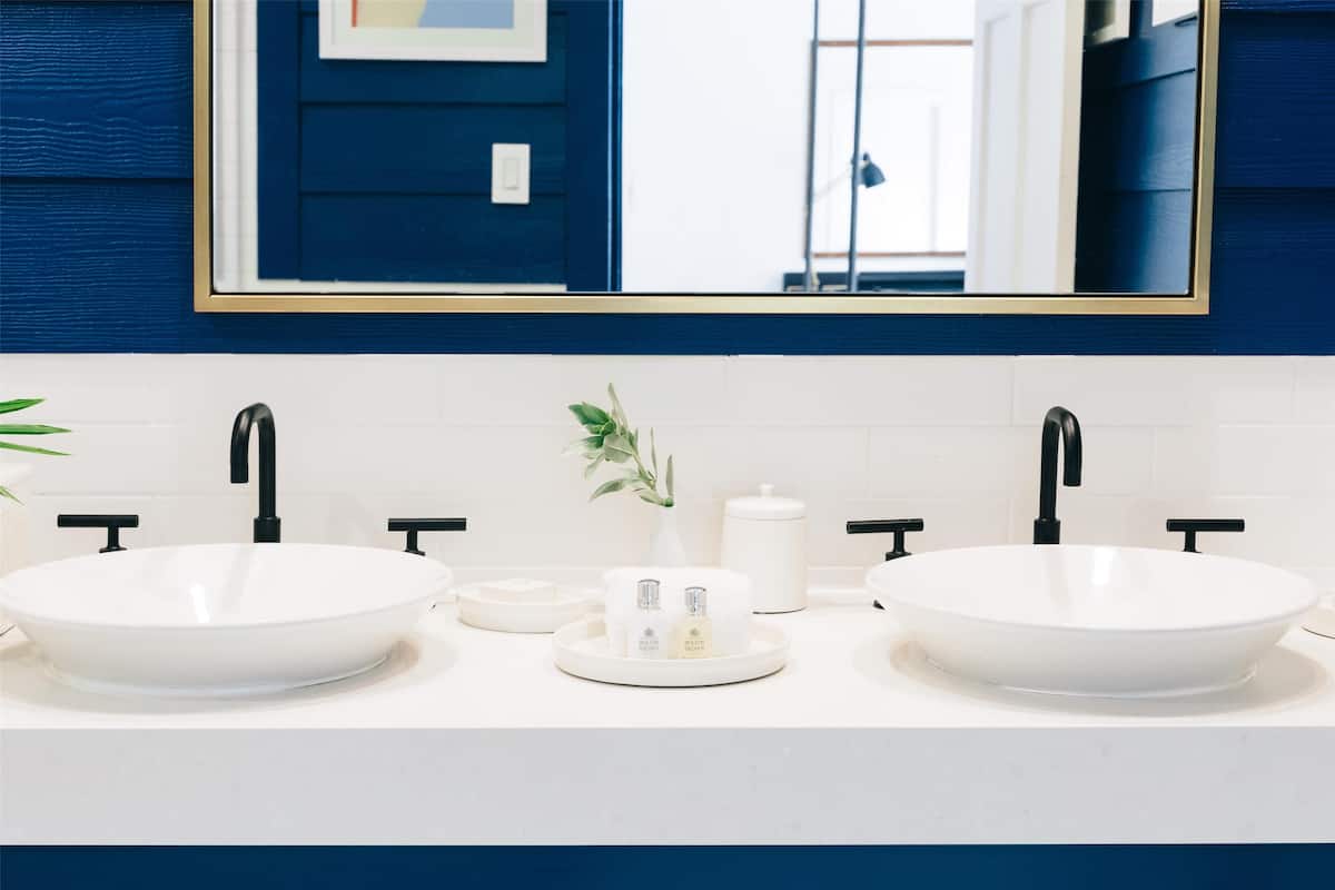 A bathroom with two white vessel sinks, black faucets, and a white countertop.
