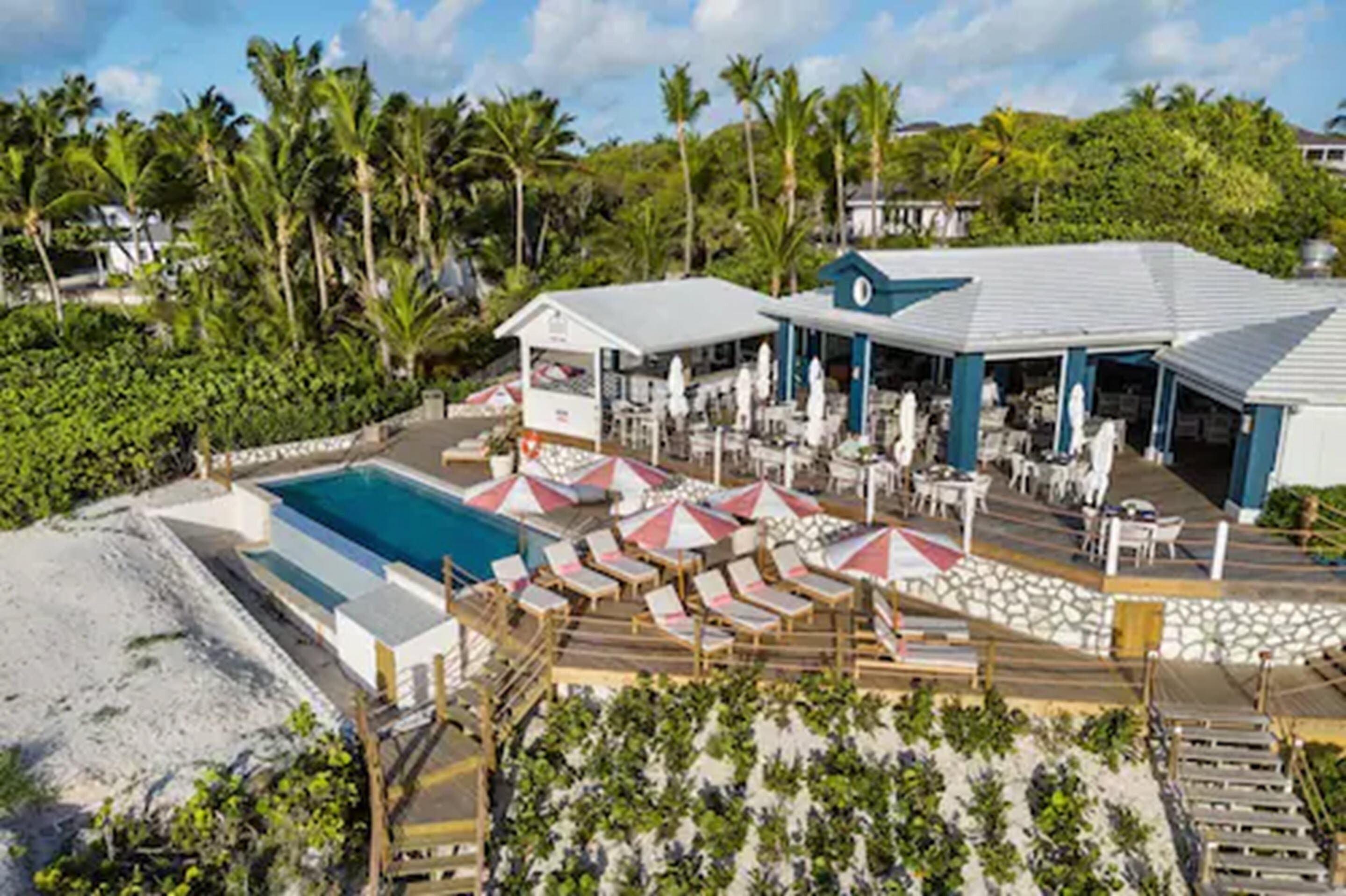 Un complexe hôtelier doté d’une piscine, de chaises longues, de parasols et d’un espace de détente abrité.