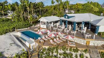 Un complexe hôtelier doté d’une piscine, de chaises longues, de parasols et d’un espace de détente abrité.
