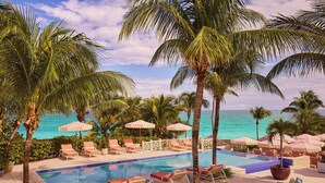 A poolside area with lounge chairs and umbrellas, overlooking a clear blue ocean. - Coral Sands Inn & Cottages (Dunmore Town)