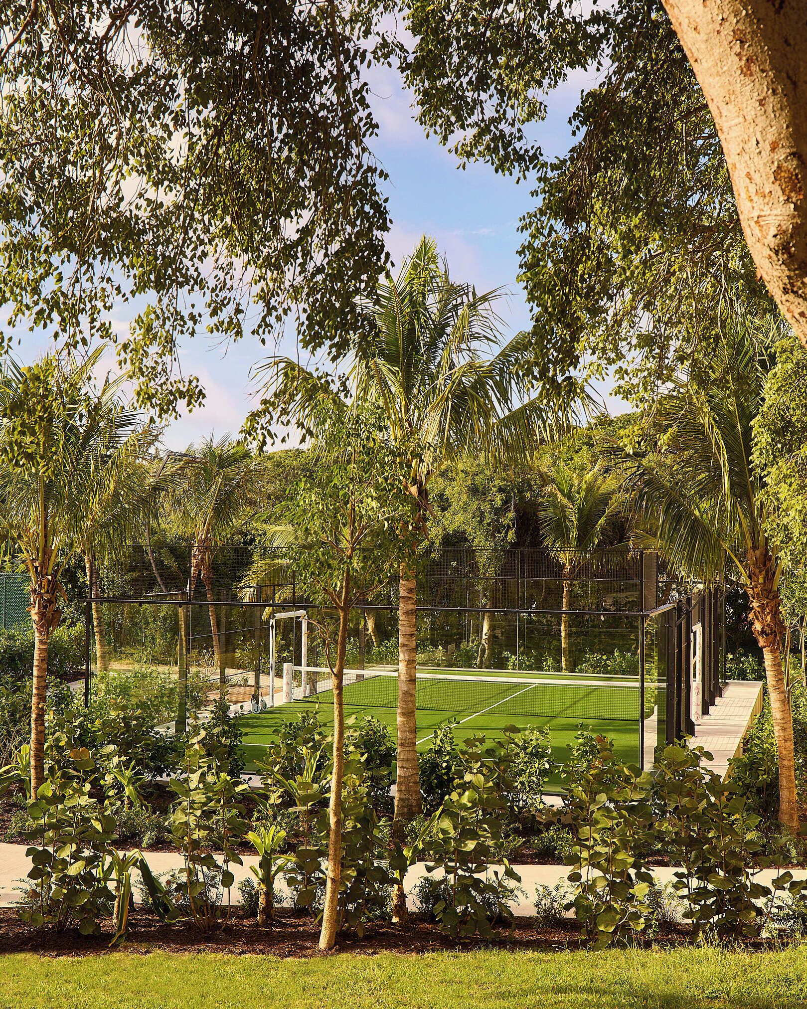 A tennis court surrounded by lush greenery and trees.